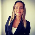 Fotografia de Soraia Arnaut Oliveira - uma mulher de cabelo loiro de expressão serena e confiante, a sorrir levemente para a câmara. Usa um blazer preto sobre um top branco, transmitindo uma aparência profissional e cuidado.