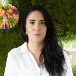 Fotografia de Inês Silveiro, uma mulher de cabelo comprido negro e olhos castanhos, com olhar sereno para a câmara. Usa uma camisa branca em contraste com o fundo verde, comum em fotos corporativas.