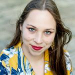 Fotografia de Cátia Diogo, uma mulher de olhos azuis e cabelo castanho a sorrir levemente para a câmara. Usa batom vermelho e uma camisola com padrões amarelo e azul.