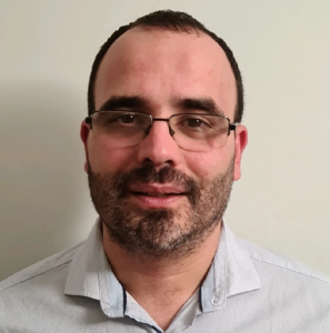 Fotografia de Luis Gomes, um homem de cabelo curto e barba preta, a olhar diretamente para a câmera com um leve sorriso. Usa óculos e o fundo é branco, comum em retratos corporativos.