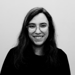 Fotografia de Andreia Peixoto, uma mulher de olhos castanhos e cabelo preto a sorrir para a câmera. Usa óculos e a foto é a preto e branco.