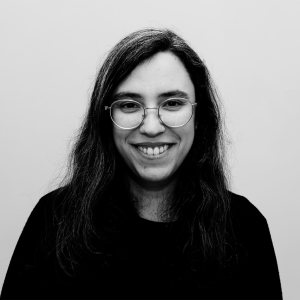 Fotografia de Andreia Peixoto, uma mulher de olhos castanhos e cabelo preto a sorrir para a câmera. Usa óculos e a foto é a preto e branco.