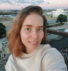 Fotografia de Oleksandra Khalimon, uma mulher de cabelo castanho claro e olhos verdes a sorrir levemente para a câmara. Veste uma camisola creme e o fundo é num ambiente outdoor, conferindo um ar descontraído.