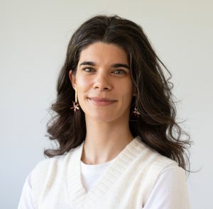 Fotografia de Mariana Gil, uma mulher de cabelo preto e olhos verdes a sorrir levemente para a câmara. Veste uma camisola e colete branco. O fundo é branco, comum em fotos corporativas.